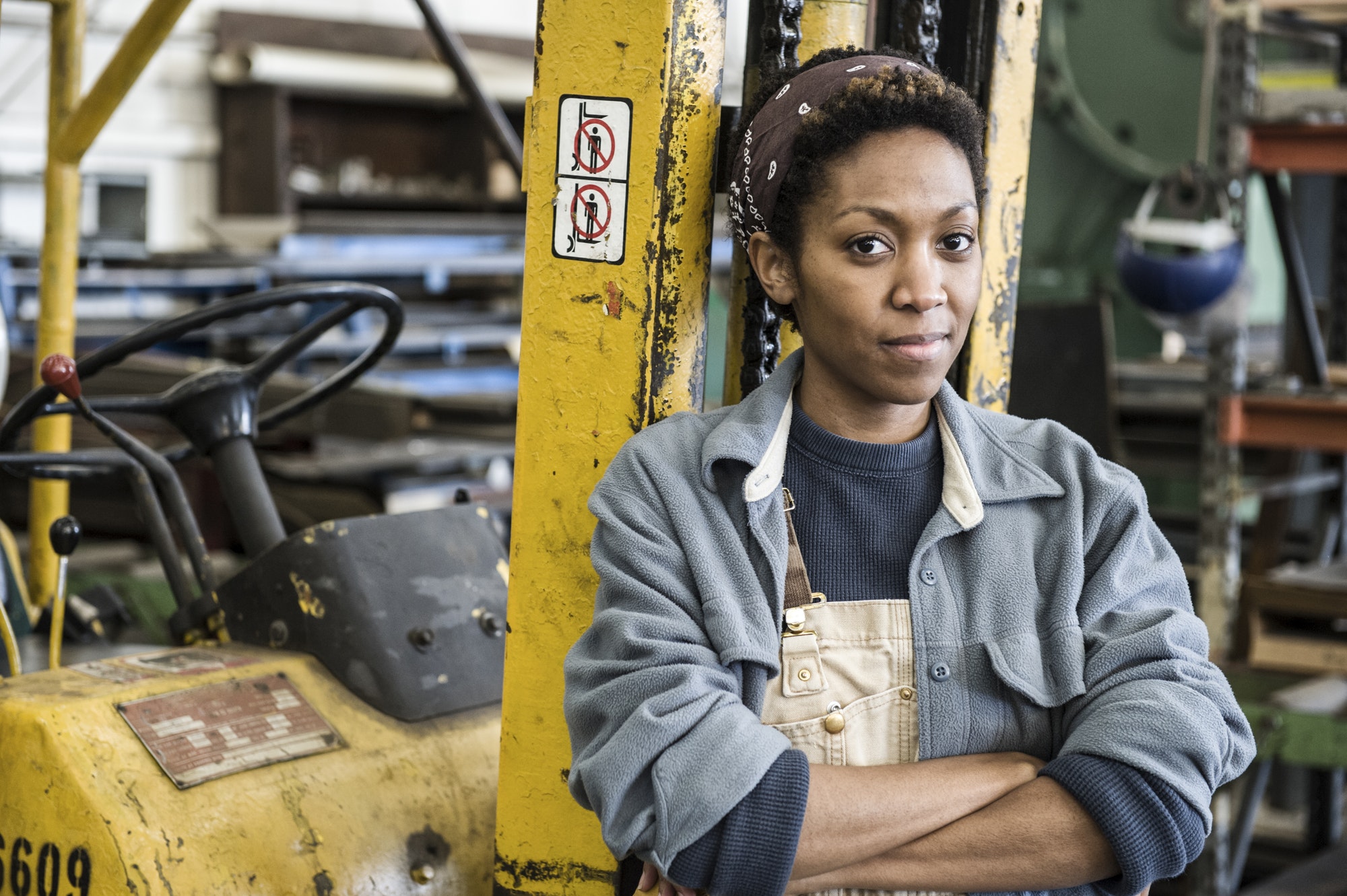Black woman factory worker and a fork lift in a sheet metal factory.