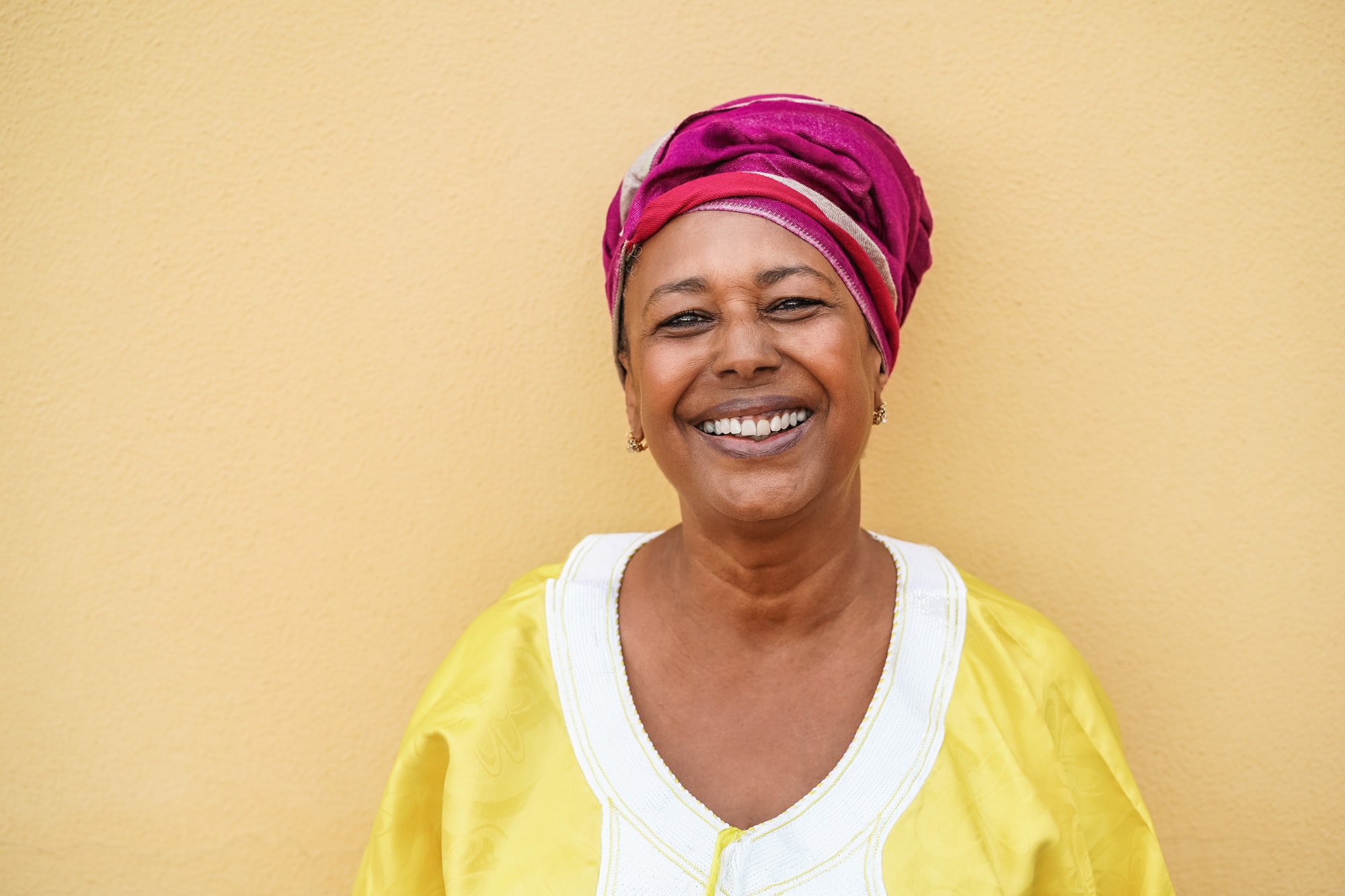 Happy senior african woman wearing traditional dress looking at camera